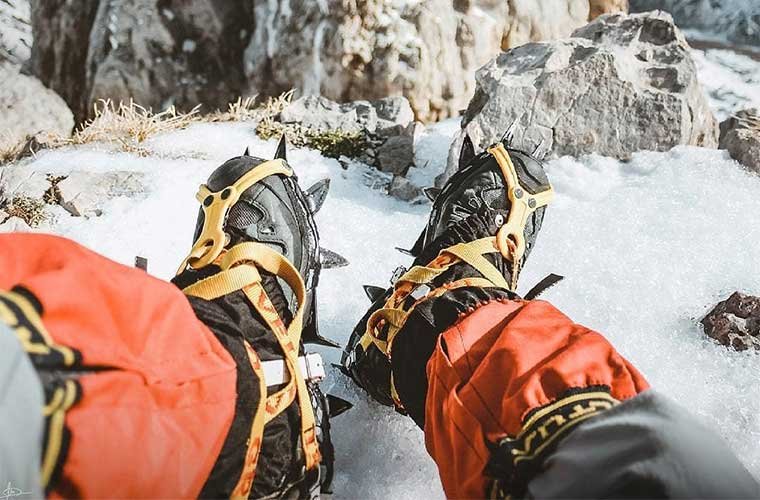 Escalador de hielo con crampones en botas de montaña - fotografía